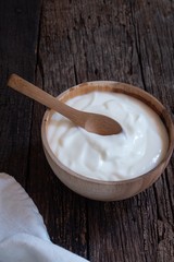 Natural homemade plain organic yogurt in wood bowl on wood texture background