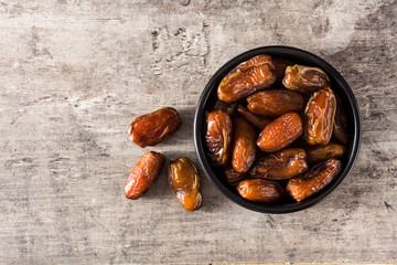 Dates in black bowl on wooden table. Top view. Copyspace