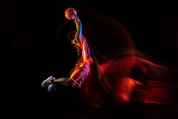 Catching the sun. African-american young basketball player of red team in action and neon lights...