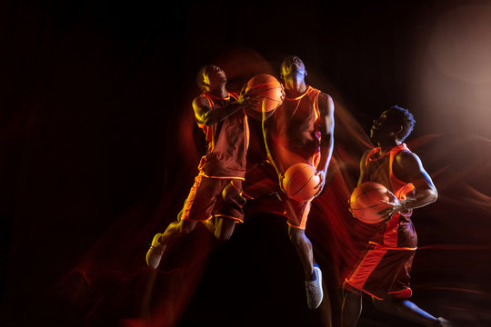 Best team ever. African-american young basketball player of red team in action and neon lights over dark studio background. Concept of sport, movement, energy and dynamic, healthy lifestyle.