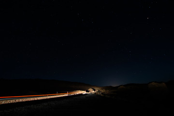 night photos on the Teide volcano in Tenerife. Images of the starry sky at night with the glow of the cities on the horizon and light trail of a car