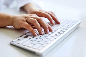 Female doctor typing on keyboard of computer in office