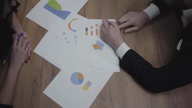 Shot of graphic data templates table with unrecognizable business people analyzing growth rates and trends. Above view. Workplace. Office space.