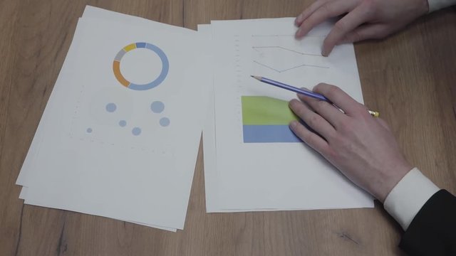 Shot of graphic data templates table with unrecognizable business people analyzing growth rates and trends. Above view. Workplace. Office space.