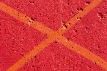 Beautiful horizontal texture of part of old concrete wall painted in orange and red color with diagonal yellow cross and holes on the photo