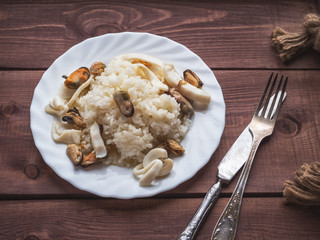 Breakfast of rice and seafood on a white plate on a rustic raisin tray