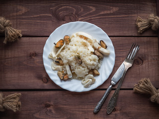 Hot breakfast of rice and seafood on a white plate on a rustic tray in rustic style, cutlery