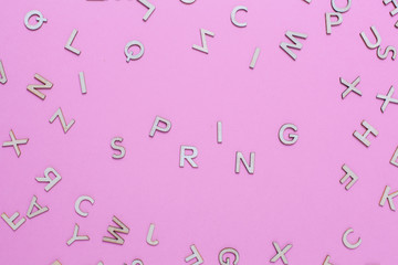 Wooden ABC alphabet letters on pink background. Spring word written with wooden letters