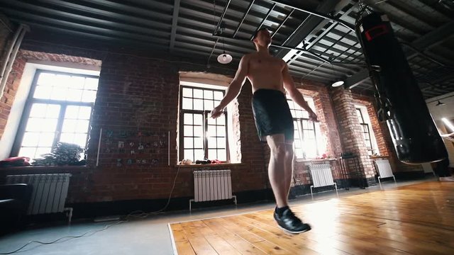 An athlete man jumping over the jump rope on training in the gym