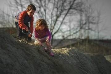 Children play on the hill of mud with a dog
