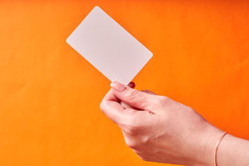 A woman's hand holds a white plastic card. Isolated card in hand