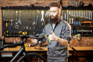 Portrait of a handsome bearded repairman in workwear at the bicycle workshop