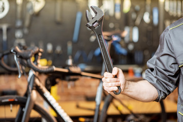 Repairman holding cleavage key in the bicycle workshop, close-up view