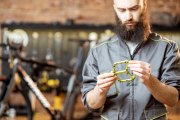 Repairman holding bicycle pedals before installing them at the bicycle workshop
