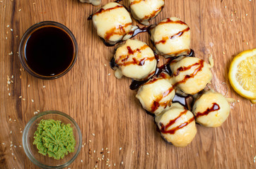 Unusual sushi rolls on a wooden table. Ukrainian sushi rolls with baked cheese and crabs