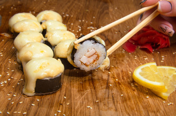 Unusual sushi rolls on a wooden table. Ukrainian sushi rolls with baked cheese and crabs