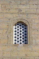Front bottom view of old masonry perforated white stone window