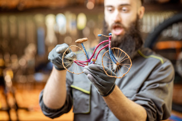 Repairman holding a small toy bicycle at the bicycle workshop