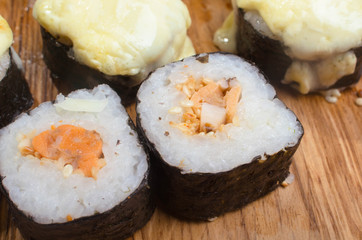 Unusual sushi rolls on a wooden table. Ukrainian sushi rolls with baked cheese and crabs