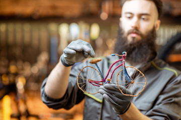 Repairman holding a small toy bicycle at the bicycle workshop