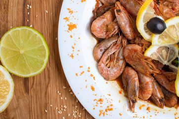 Appetizing shrimps in soy sauce on a white dish. Shrimps with olives and lemon. Restaurant seafood dish. Tasty diet food