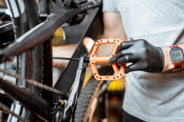 Obraz premium Repairman installing new pedals on a mountain bicycle at the workshop