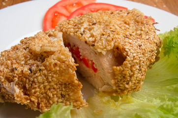 Chicken breast in sesame deep-fried. Chicken fillet stuffed with cheese and bell pepper. Restaurant dish on a white plate