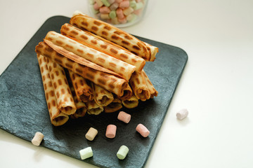 waffle tubes on black Board and marshmallow on white background