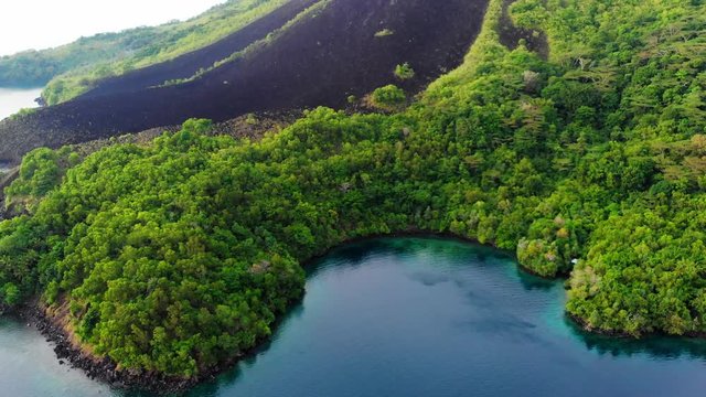 Aerial: flying over Banda Islands active volcano Gunung Api lava flows Maluku Indonesia lush green forest turquoise water coral reef scenic travel destination