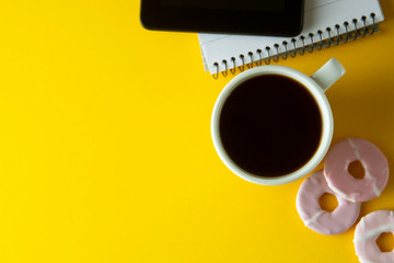 Styled yellow, food backdrop. Unhealthy lunch, snack with coffee, cookies, digital tablet. work space, lunch at work table. Top view, copy space.