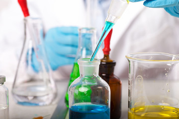 Laboratory beaker in analyst's hand in plastic glove