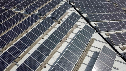 Solar panels spread across an industrial roof - Aerial image.