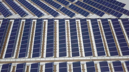Solar panels spread across an industrial roof - Aerial image.