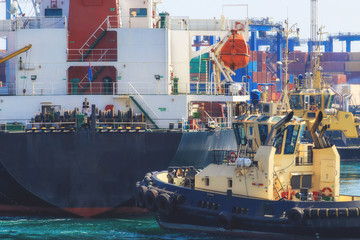 Tugboat assisting Cargo Ship maneuvered into the Port of Odessa, Ukraine. Handling of goods and the work of a commercial port.