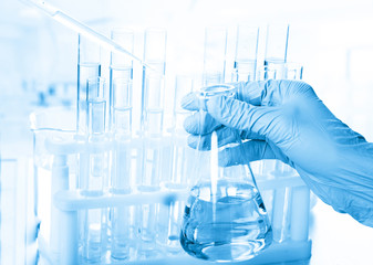 Laboratory beaker in analyst's hand in plastic glove