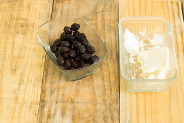 Green pepper and olives and feta cheese in glass dish on dirty wooden background