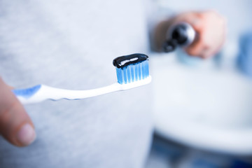 Toothpaste and brush of black activated carbon. Charcoal in the hands of a woman. 