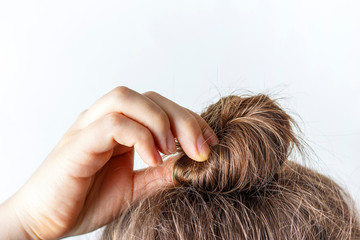 Female hand correct the bun on white background. Modern fast hairstyle.