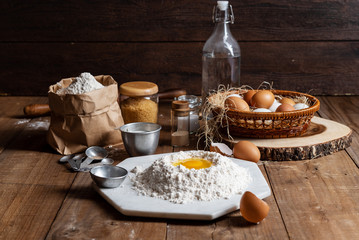 Flour with yolk egg and A lot of eggs put in the basket are place on the wooden table for cooking something.