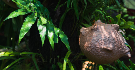 Decorative cute clay fish statue decorated in the tropical green garden.