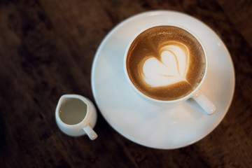 a cup of hot latte art coffee on wooden table