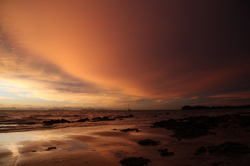 Fototapeta na wymiar Sunset after heavy rain with arcus shelf storm clouds and stones in the ocean on tropical island Ko Lanta, Thailand