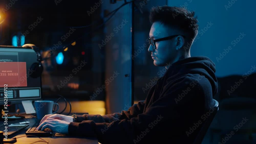 Wall mural cybercrime, hacking and technology concept - asian male hacker writing code or using computer virus 