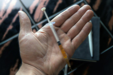 syringe in a person's hand, on a notepad background, short focus, toning