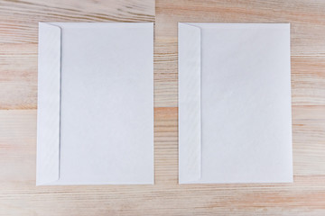 two empty white envelopes on a wooden desk