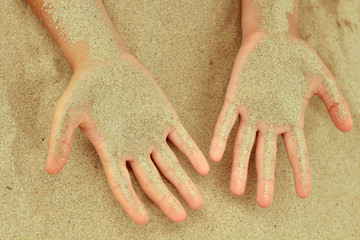 sand passes through the hands of a child