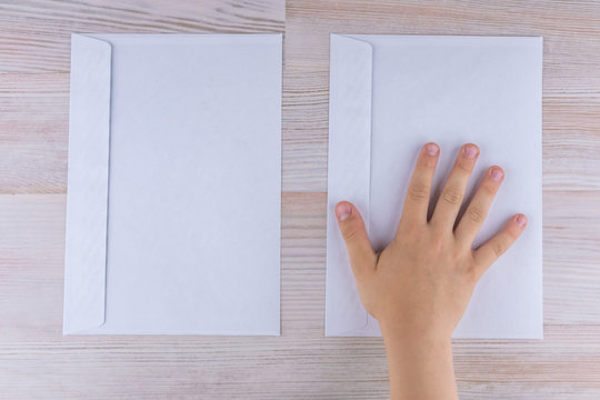 the boy makes a choice of two envelopes, laying his hand on the right, reduced contrast
