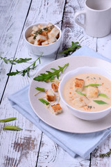 Cream soup with croutons, green onion and cheese in a white bowl