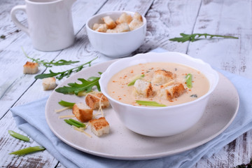 Cream soup with croutons, green onion and cheese in a white bowl