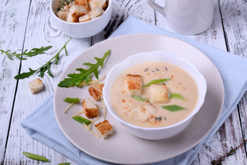 Cream soup with croutons, green onion and cheese in a white bowl
